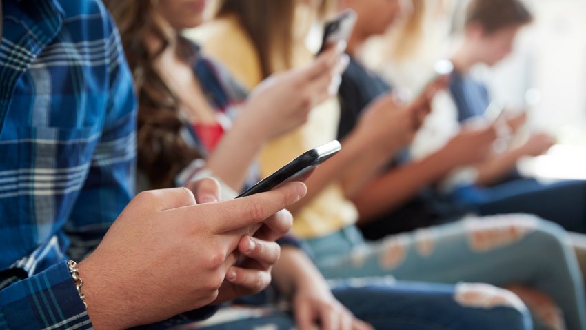 Close Up Of A Line Of High School Students Using Mobile Phones