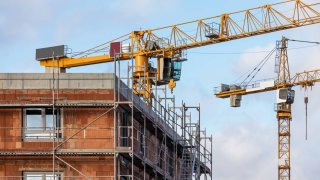 Construction site of a residential building with scaffolding and large cranes