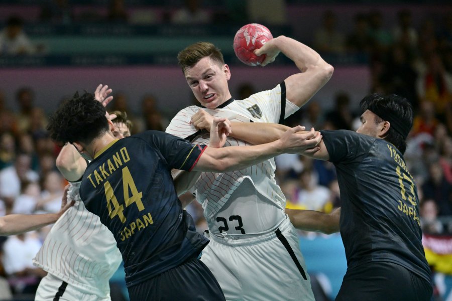 Germany's Christoph Steinert attempts to score past Japan's Sota Takano and Japan's pivot Shuichi Yoshida during the Men's Preliminary Round Group A handball match between Japan and Germany of the Paris 2024 Olympic Games.