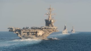 This handout photo provided by the US Navy shows the aircraft carrier USS Abraham Lincoln, left, in 2019.