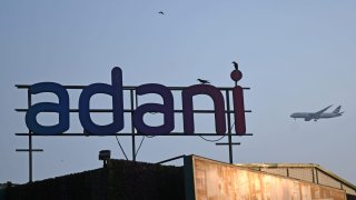 An aeroplane flies behind the Adani logo near a building construction site in Mumbai. Adani group is one of the India’s largest multinational company with a diversified business portfolio.