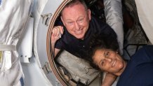 NASA astronauts Butch Wilmore, left, and Suni Williams pose inside the hatch connecting Boeing's Starliner to the International Space Station on