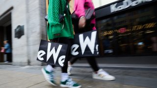 Women with KaDeWe carrier bags walk past the entrance to the Kaufhaus des Westens department store. 