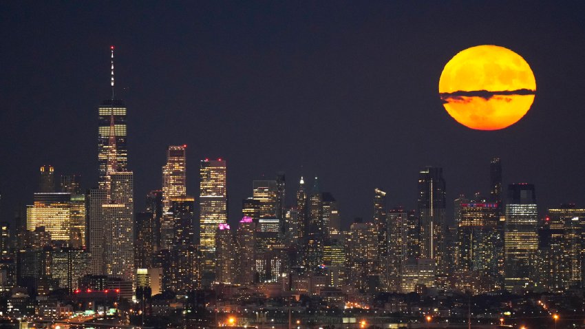 FILE – The moon rises through clouds over the skyline of lower Manhattan in this view from West Orange, N.J., Tuesday, Aug. 1, 2023, during a supermoon period.