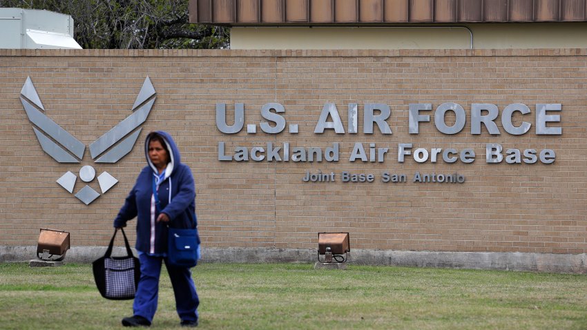 FILE - A pedestrian passes the main gate at Lackland Air Force Base in San Antonio,