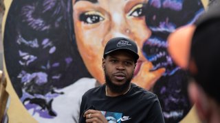 File - Kenneth Walker, boyfriend of Breonna Taylor, stands in front of a portrait of Taylor during a protest memorial for her in Jefferson Square Park on March 13, 2021 in Louisville, Kentucky.