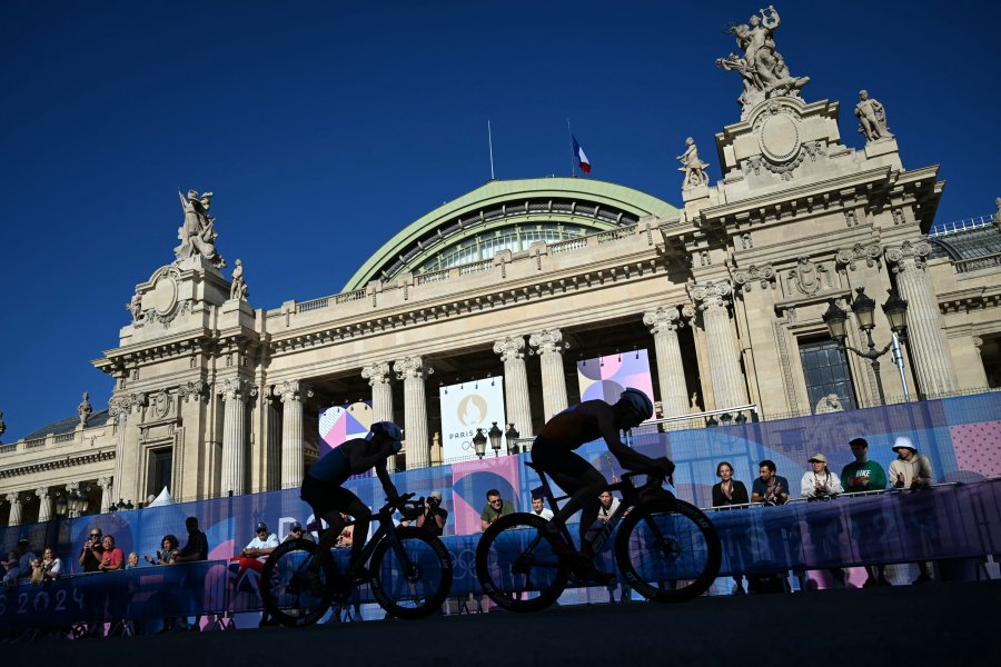 Netherlands' Richard Murray and France's Leo Bergere ride past Grand Palais as they compete in the cycling race, during the mixed's relay triathlon, at the Paris 2024 Olympic Games, in central Paris, on August 5, 2024