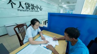 HAIAN, CHINA – JULY 22, 2024 – A staff member of a personal loan center of a bank handles personal loans for customers in Haian, East China’s Jiangsu province, July 22, 2024.