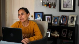 Claudia Alleman sits in front of her computer, against a backdrop of photos of her family, in the living room of her family home in South Gate on April 18, 2024. The Alleman family will be impacted when the federal internet subsidy program Affordable Connectivity Program will run out of funds next week. 