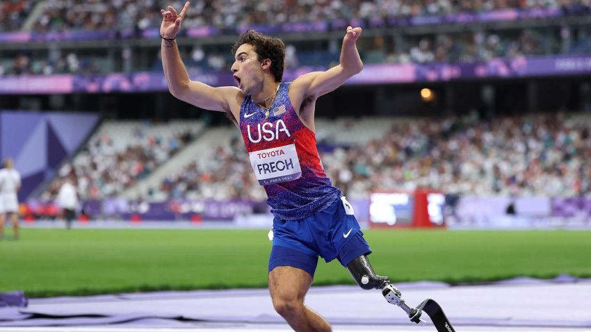 Ezra Frech holds his arms in the air and starts to run around the track as he celebrates a gold medal