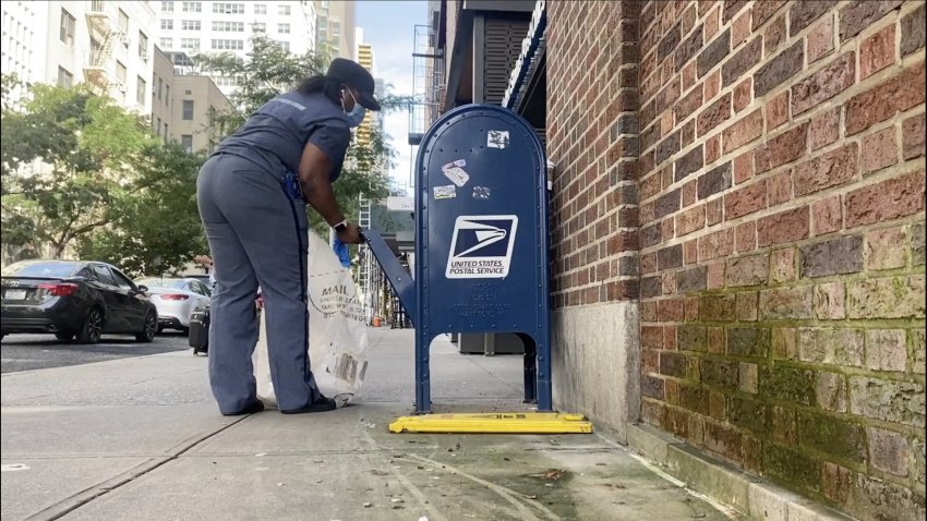 A mail carrier checks a mailbox