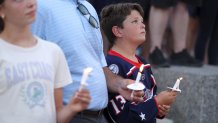 Blue Jackets fan Hudson Saad of Columbus, has a moment of silence during the candlelight vigil to honor Columbus Blue Jackets hockey player Johnny Gaudreau, outside of Nationwide Arena in Columbus, Ohio, Thursday, Sept. 4, 2024. Gaudreau and his brother Matthew were killed by a motor vehicle last week while riding bicycles. (AP Photo/Joe Maiorana)