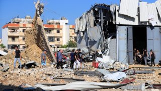 People gather at the site of an Israeli airstrike that hit a hangar in the southern town of Jiyeh, Lebanon, Wednesday, Sept. 25, 2024.