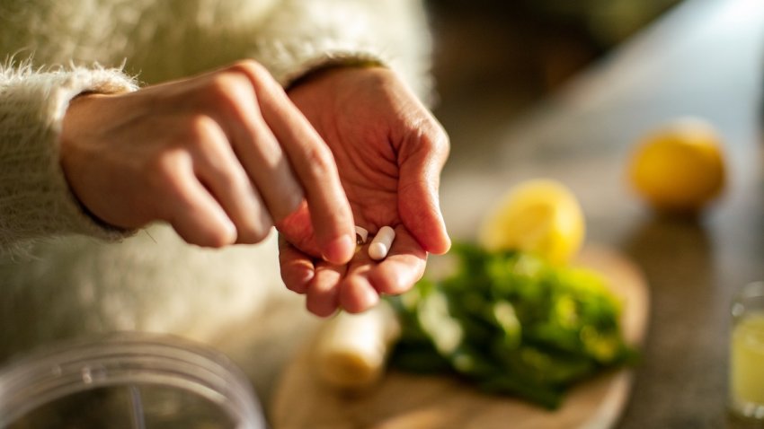 Young woman taking a health supplement in the kitchen