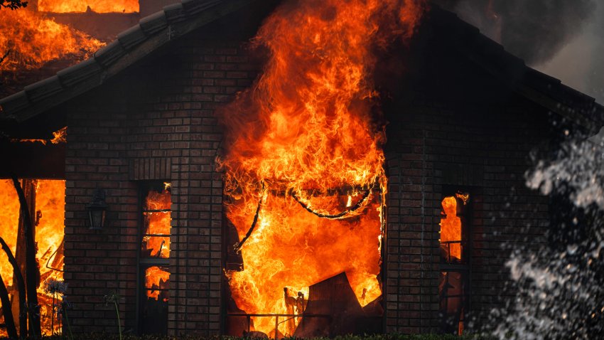 RIVERSIDE, CALIFORNIA, UNITED STATES – 2024/07/21: Flames flow from a living room window of a Riverside home as it burns down. The fire in Riverside County destroyed at least three homes and caused $11 million in damage. The fire prompted evacuation orders and warnings. Riverside Mayor Patricia Lock Dawson reported that six structures were destroyed and seven others damaged, with more damage assessments pending. Over 500 acres were scorched, but the fire was fully contained by Monday morning. An investigation into the cause is still ongoing. (Photo by Jon Putman/SOPA Images/LightRocket via Getty Images)