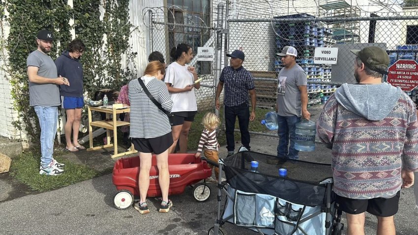 People wait to gather water at Mountain Valley Water in the aftermath of Hurricane Helene in West Asheville, N.C., Monday, Sept. 30, 2024. (AP Photo/Jeffrey Collins)