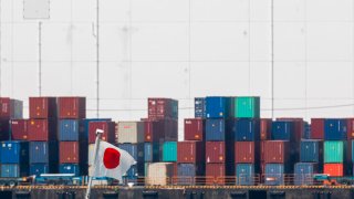 A flag of Japan flies near cargo containers at Tokyo’s Odaiba Waterfront on August 6, 2020.