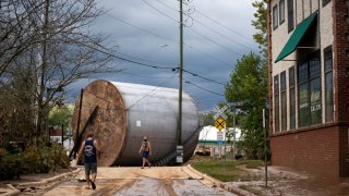 Men inspect the damage from flooding in the aftermath of Hurricane Helene on Sept. 28, 2024 in Asheville, North Carolina.