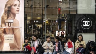 Pedestrians holding Chinese flags outside a Chanel SA store on Nanjing East Road in Shanghai, China, on Wednesday, Oct. 2, 2024. 