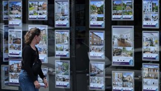 A pedestrians looks at residential properties displayed for sale in the window of an estate agents’ in Windsor, west of London.