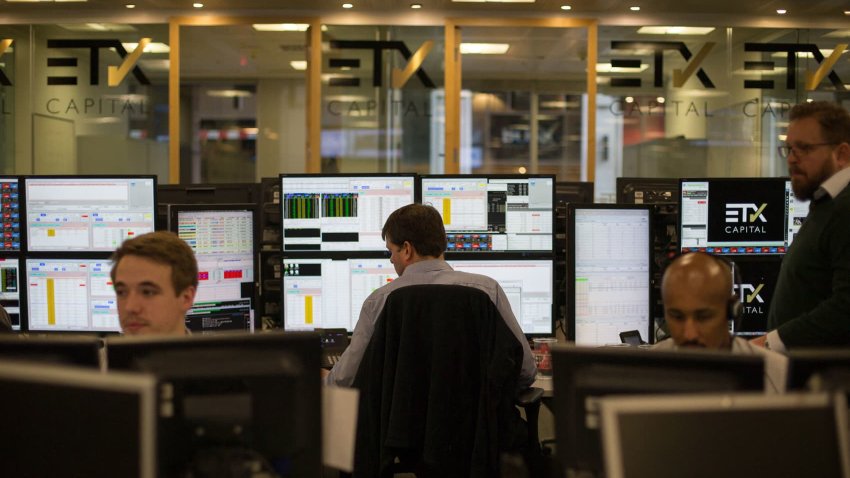 Traders sit in front of trading screens at ETX Capital in central London on January 3, 2017. London’s FTSE 100 reached a historic peak at 7,205.21 points in morning trade, extending a record run seen in the final week of 2016, before easing back from its highs. 