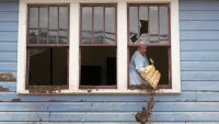 Ben Phillips scoops mud out a window of his house