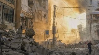 A man runs for cover as a smoke raises in the background following an Israeli airstrike in Dahiyeh, Beirut, Lebanon, Friday, Oct. 4, 2024.