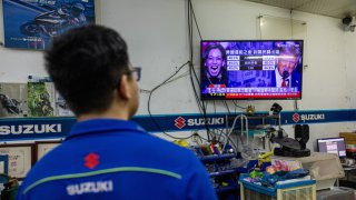 A worker at a motorcycle supply shop in Taipei, Taiwan, watches a television broadcast covering the U.S. Presidential election on November 05, 2024.