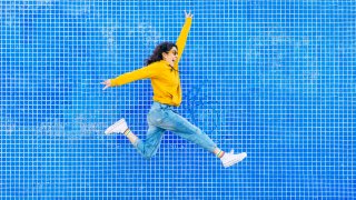 Woman jumping in front of a blue background