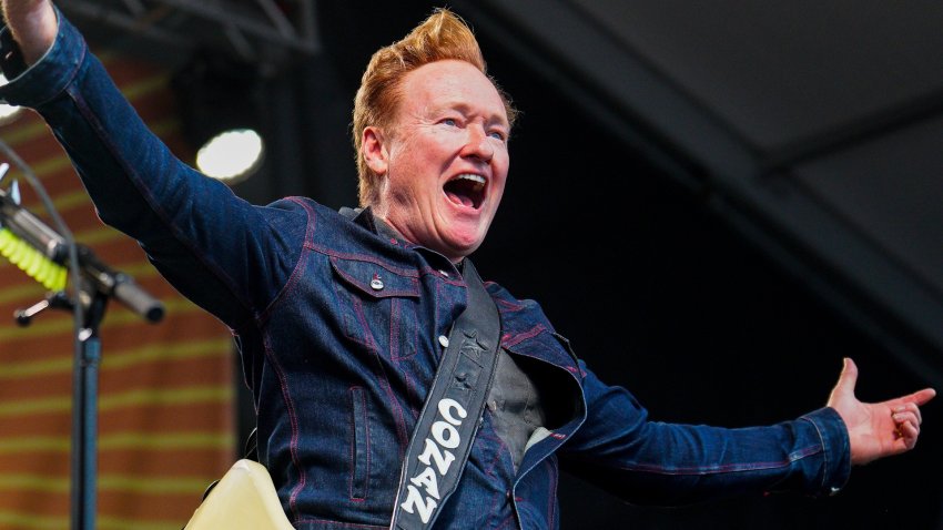 Conan O'Brien holds his arms out on stage