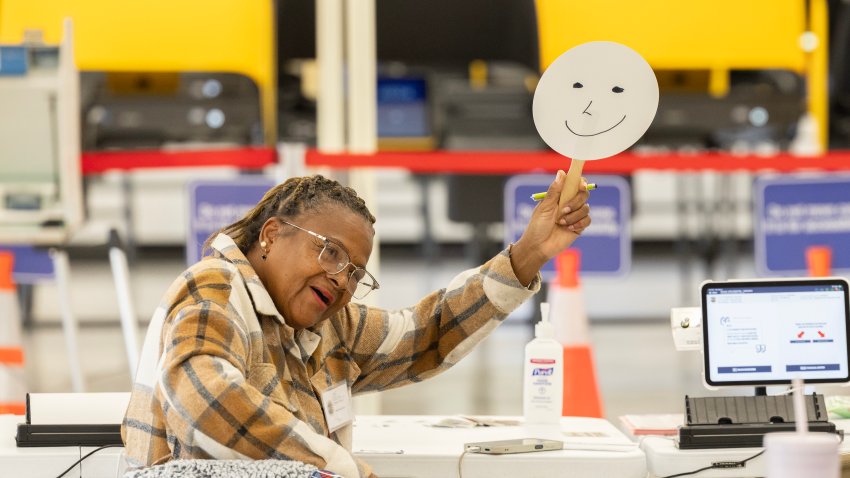 NORWALK, CA – NOVEMBER 04: Volunteer Sheila Cooper waves her sign to voters walking in for early voting at the Los Angeles County Registrar-Recorder / County Clerk builidng in Norwalk, CA on Monday, Nov. 4, 2024. (Myung J. Chun / Los Angeles Times via Getty Images)