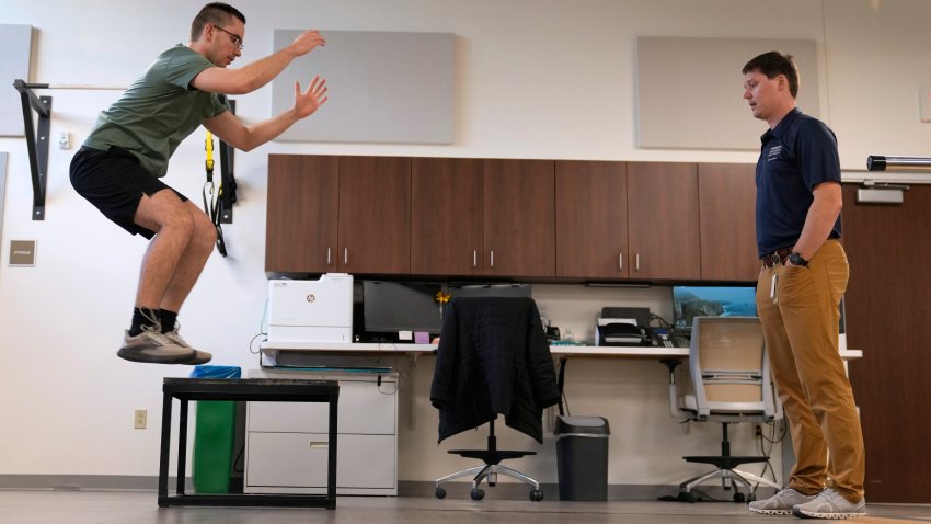 Physical therapist Tyler Detmer, right, works with patient Jacob Bullard at WashU