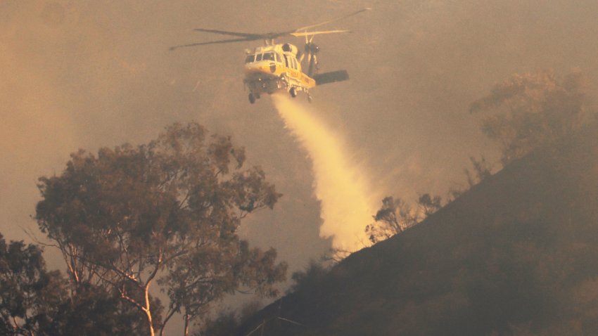 AQ helicopter drops water as the Franklin Fire grows in Malibu, California, on December 10, 2024. A wind-fanned wildfire quickly spread early on Tuesday in Malibu, threatening homes and businesses in the coastal California community where many Hollywood elites reside. (Photo by DAVID SWANSON / AFP) (Photo by DAVID SWANSON/AFP via Getty Images)