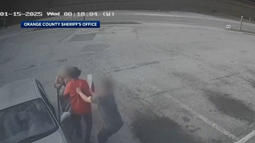 Surveillance camera footage of a woman being attacked in a parking lot.