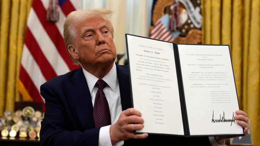 President Donald Trump holding up a order for clemency for anti-abortion protesters as he signs executive orders in the Oval Office of the White House, Thursday, Jan. 23, 2025, in Washington.