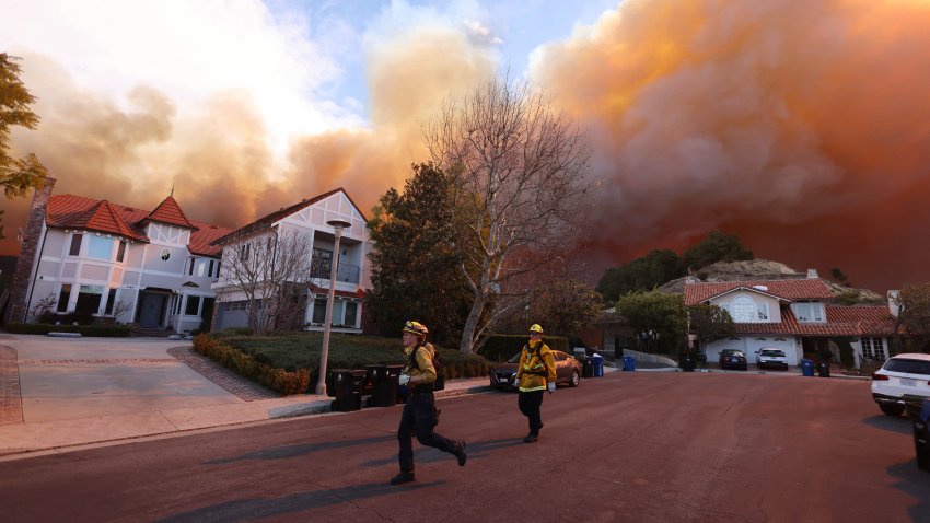 Firefighters run as a brush fire burns in Pacific Palisades, California on January 7, 2025. A fast-moving brushfire in a Los Angeles suburb burned buildings and sparked evacuations Tuesday as “life threatening” winds whipped the region. More than 200 acres (80 hectares) was burning in Pacific Palisades, a upscale spot with multi-million dollar homes in the Santa Monica Mountains, shuttering a key highway and blanketing the area with thick smoke. (Photo by David Swanson / AFP) (Photo by DAVID SWANSON/AFP via Getty Images)