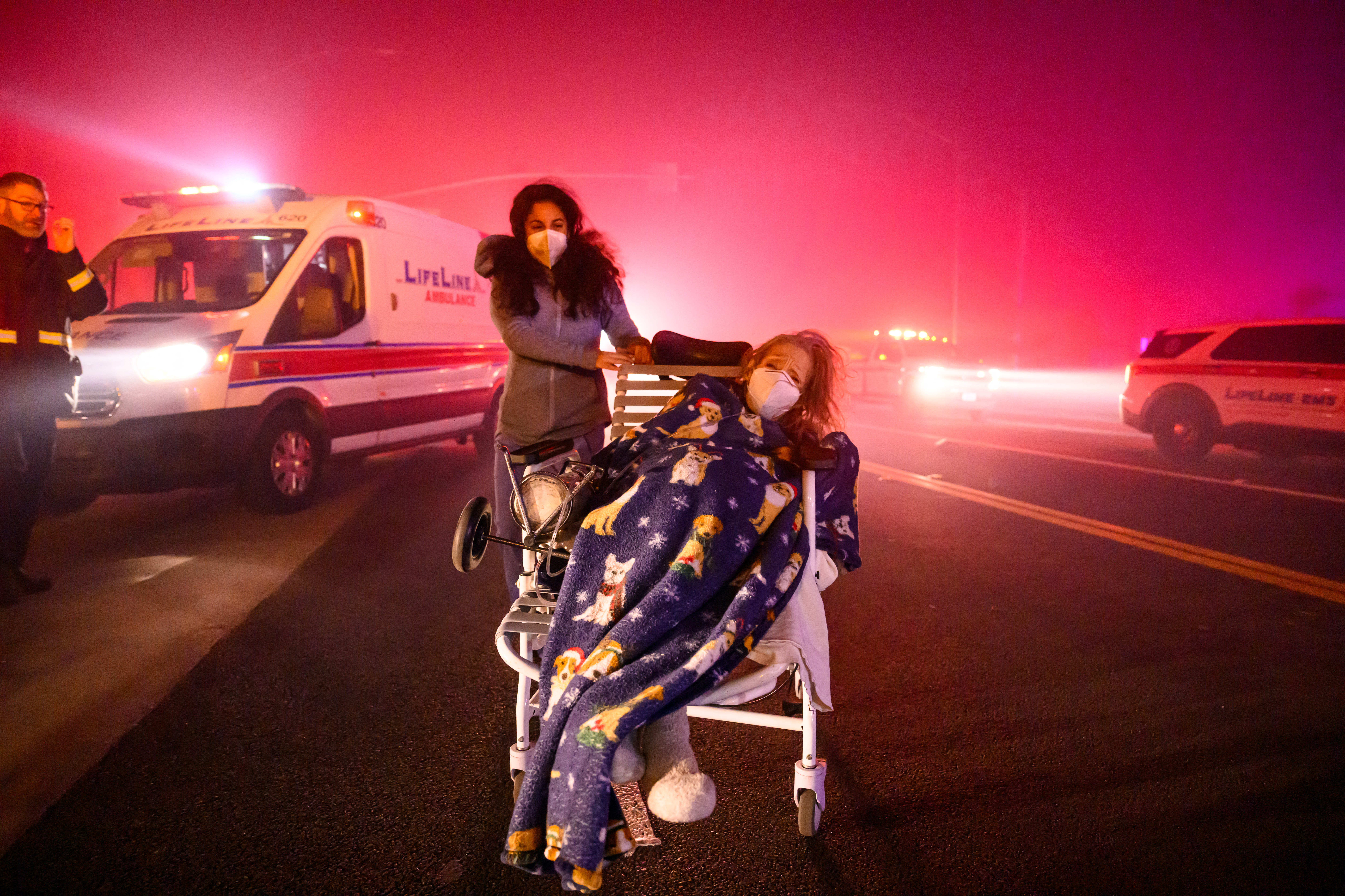 Elderly patients are quickly evacuated into emergency vehicles as embers and flames approach during the Eaton fire in Pasadena, California on January 7, 2025. (Photo by JOSH EDELSON/AFP via Getty Images)