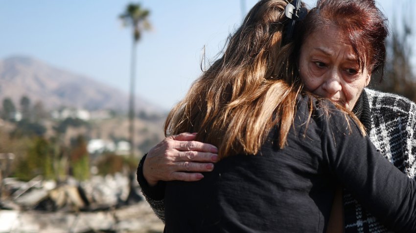 PASADENA, CALIFORNIA – JANUARY 11: Araxy Manookian receives a hug in front of her home which was destroyed in the Eaton Fire as wildfires cause damage and loss through the LA region on January 11, 2025 in Pasadena, California. She has lived there since 1997. Multiple wildfires fueled by intense Santa Ana Winds are burning across Los Angeles County. Reportedly at least 10 people have died with over 180,000 people having been under evacuation orders. Over 9,000 structures have been damaged or burned while more than more than 25,000 acres were burning from the fires. (Photo by Mario Tama/Getty Images)