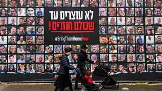 Pedestrians walk past the portraits of Israeli hostages held in the Gaza Strip, in Jerusalem on Friday