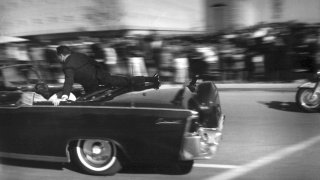 In this Nov. 22, 1963 file photo, the limousine carrying mortally wounded President John F. Kennedy races toward the hospital seconds after he was shot in Dallas. Secret Service agent Clinton Hill is riding on the back of the car, Nellie Connally, wife of Texas Gov. John Connally, bends over her wounded husband, and first lady Jacqueline Kennedy leans over the president.