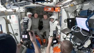 NASA astronaut Butch Wilmore, Roscosmos cosmonaut Aleksandr Gorbunov and NASA astronauts Nick Hague and Suni Williams pose for a photo at the hatch a SpaceX Crew Dragon capsule before closing the hatch in preparation for undocking from the ISS to begin their return to Earth March 17, 2025 in this still image taken from video.