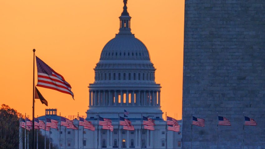 Sunrise turns the sky orange behind the U.S. Capitol building as it illuminates the U.S. Flags circling the base of the Washington Monument on March 23, 2025, in Washington, DC.