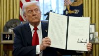 U.S. President Donald Trump shows a signed document in the Oval Office at the White House in Washington, D.C., U.S., March 26, 2025. 