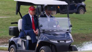 President Donald Trump and his son, Eric Trump, drive in a golf cart after he arrived on Marine One at the LIV Golf Miami golf tournament at Trump National Doral.
