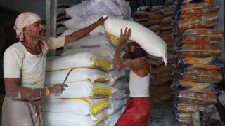 A laborer carries a sack filled with refined wheat flour to load it onto a supply truck at a wholesale market in Kolkata, India, on April 10, 2025.
