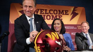 Washington Commanders managing partner Josh Harris (L) signs a Commanders helmet while joined by Washington DC Mayor Muriel Bowser (C) and NFL Commissioner Roger Goodell (R) during a news conference on construction of a new Commanders stadium on April 28, 2025 in Washington, DC.