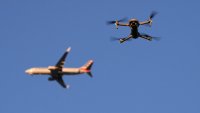 A drone hovers in airspace outside the safety perimeter surrounding St. Louis Lambert International Airport as an airliner approaches for a landing on March 10, 2025.