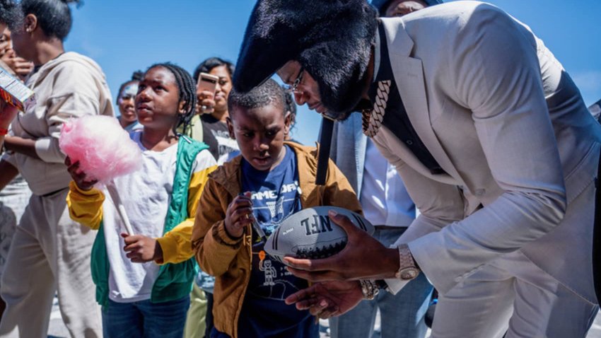 Lamar Jackson signs a football for a young fan.