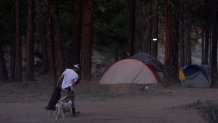 A person walks to a tent at a homeless encampment in Deschutes National Forest, Wednesday, April 30, 2025, near Bend, Ore. (AP Photo/Jenny Kane)