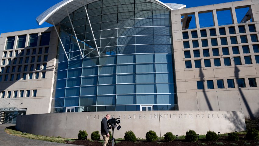 A journalist  points his camera at the US Institute of Peace in Washington, DC, on March 18, 2025. Cost-slashers of US President Donald Trump seized control on March 17 of the institute, ousting the leader of the taxpayer-funded center for conflict resolution created by Congress in 1984. (Photo by ROBERTO SCHMIDT / AFP) (Photo by ROBERTO SCHMIDT/AFP via Getty Images)